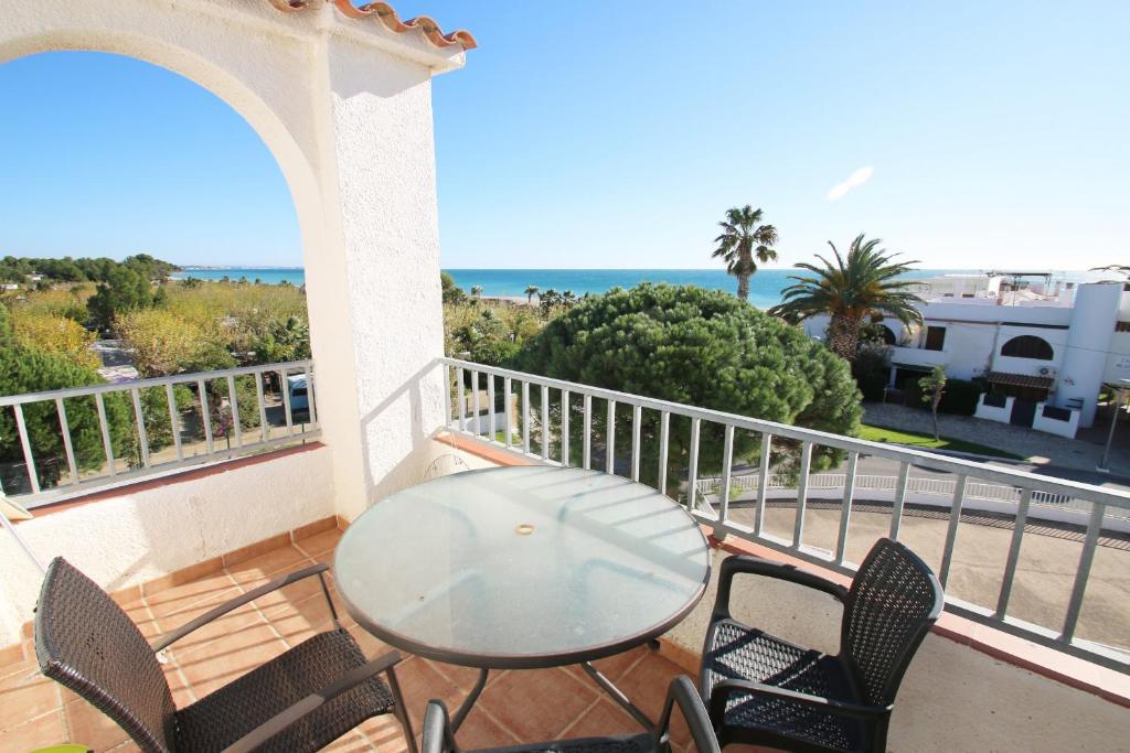 d'une table et de chaises en verre sur un balcon donnant sur l'océan. dans l'établissement Apartamento Panorama 5, à Miami Platja