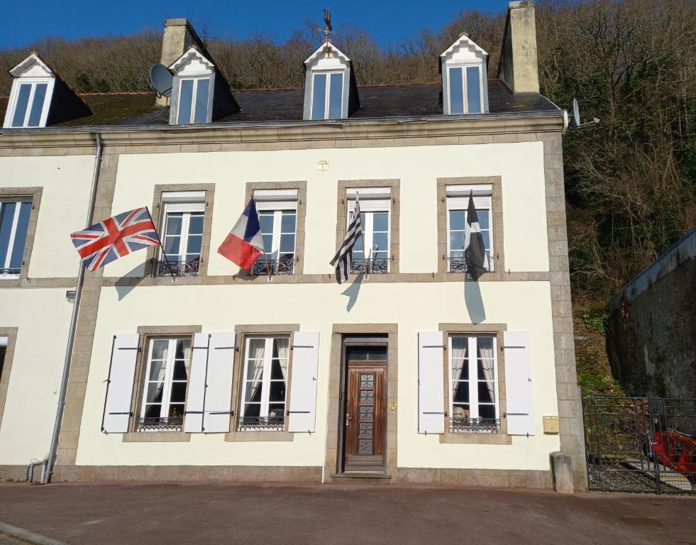 ein Haus mit Flaggen auf der Vorderseite in der Unterkunft Maison de la riviere in Port-Launay
