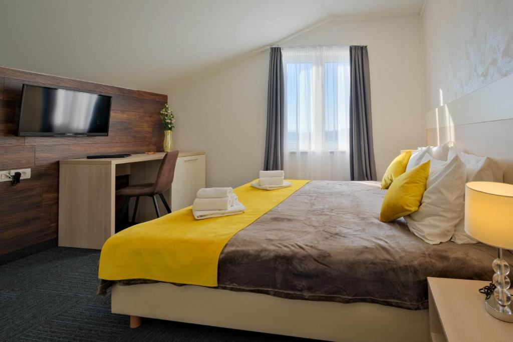 a bedroom with a large bed with a yellow blanket at Hotel Bor in Krk