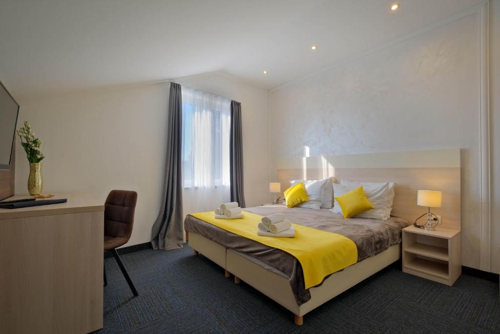 a bedroom with a bed and a desk and a window at Hotel Bor in Krk