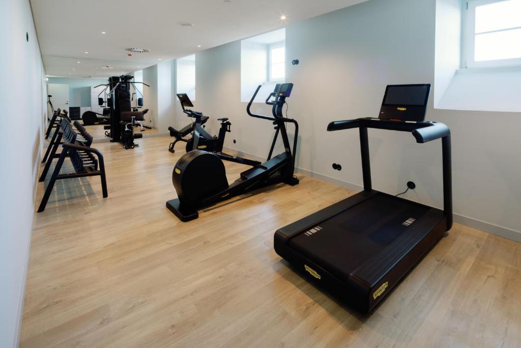 A bright fitness room with cardio machines, resistance equipment and mirrored walls.