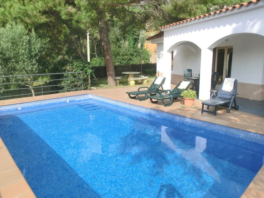 a swimming pool with two chairs and a house at 2Sena - Lloret de Mar in Lloret de Mar