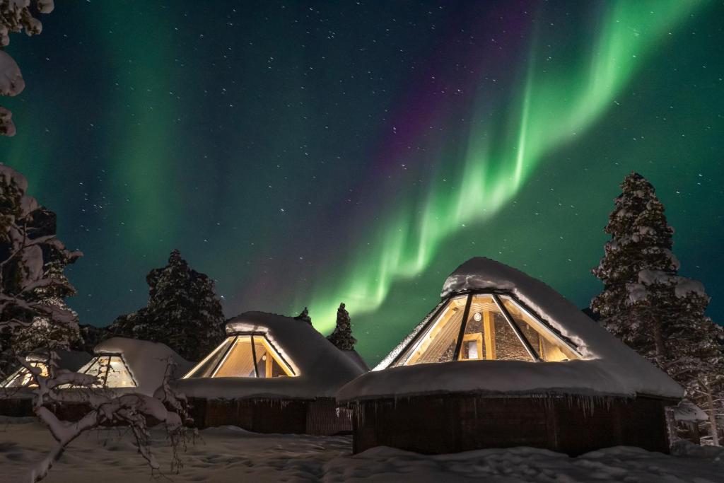 an aurora over a row of snow covered yurt at Wilderness Hotel Muotka & Igloos in Saariselka