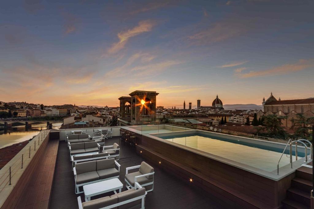 a pool on the roof of a building with chairs at Plaza Hotel Lucchesi in Florence