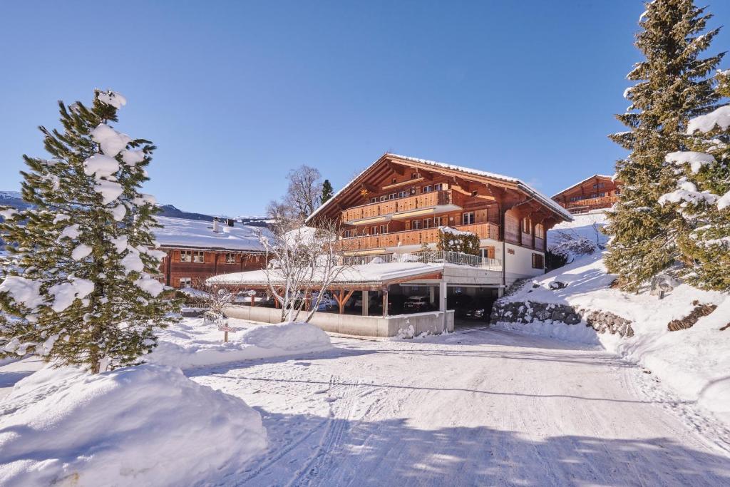una gran casa de madera en la nieve con árboles en Bielholz en Grindelwald