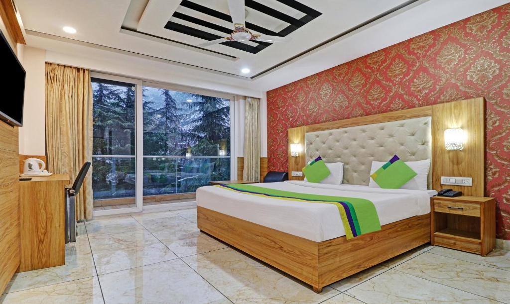 a bedroom with a large bed and a large window at Treebo Trend Akashdeep in Dharamshala