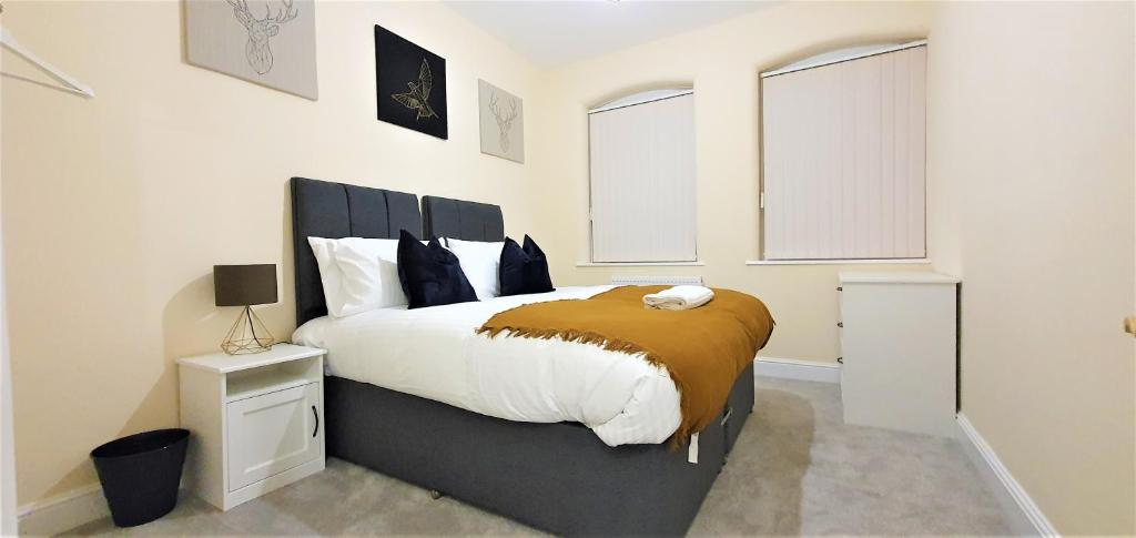 a bedroom with a large bed and two windows at Shakespeare Views - Modern Northampton Apartment in Northampton