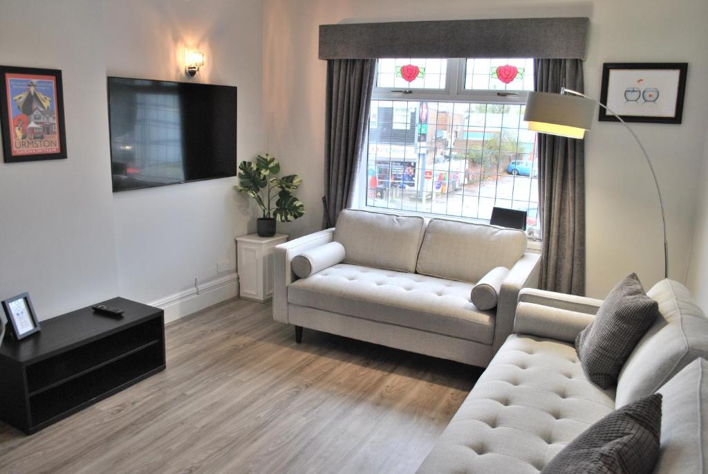 a living room with a white couch and a window at Trafford Terrace Davyhulme in Urmston