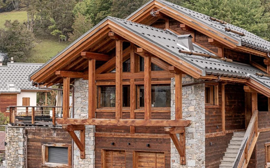 uma casa de madeira com um telhado de metal e portas de madeira em L'Or des Cimes em Valloire