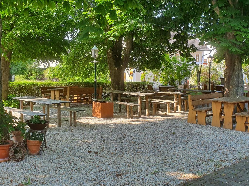 Landgasthof Geltinger في Adlkofen: مجموعة من الطاولات وكراسي التنزه تحت شجرة