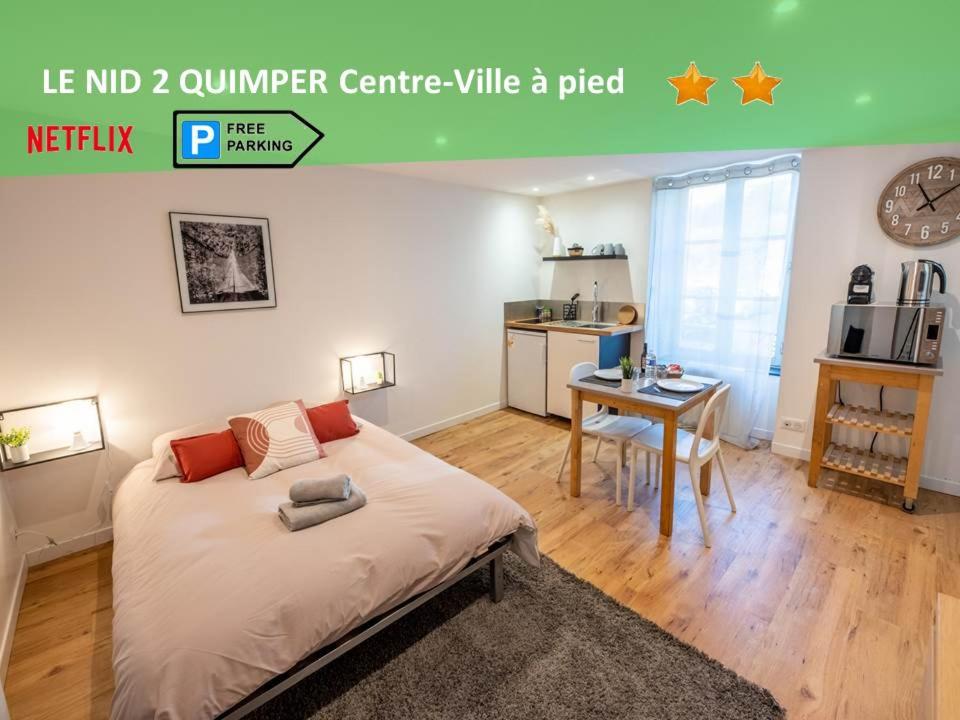 Cet appartement comprend une chambre avec un lit et une table ainsi qu'une cuisine. dans l'établissement LE NID 2 QUIMPER BY Nid'Ouest, à Quimper