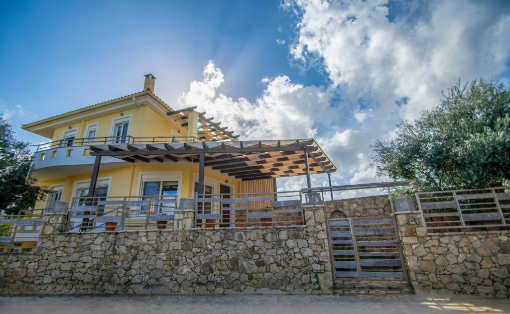żółty dom na kamiennej ścianie w obiekcie Ianthi Beach Villa w mieście Kypseli