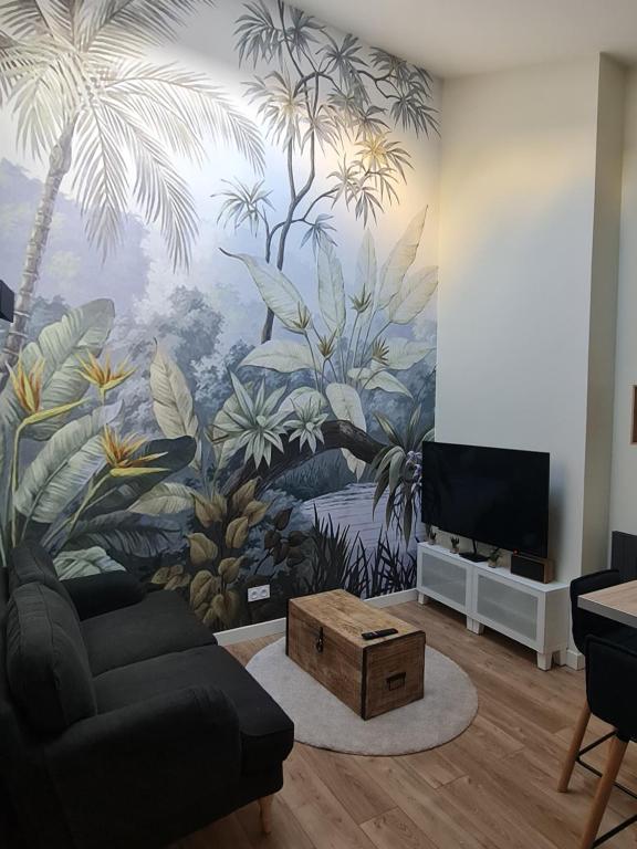 a living room with a palm tree mural on the wall at Le Petit Roche in Roche-la-Molière