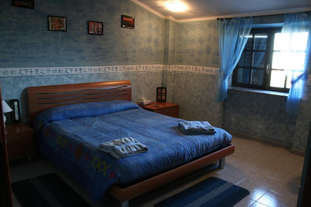 a bedroom with a bed with blue sheets and a window at Hotel Food & Drink in Altomonte