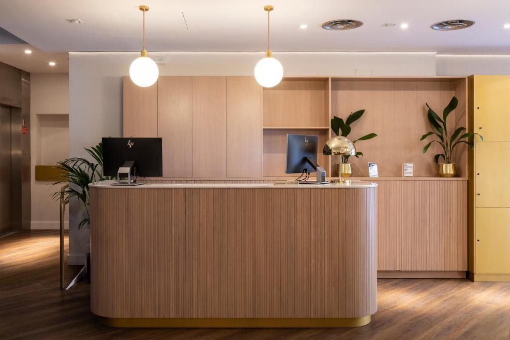 an office lobby with a reception counter with potted plants at Petit Palace Puerta del Sol in Madrid