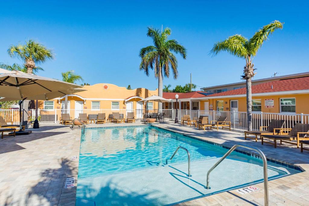 a swimming pool with tables and chairs and palm trees at Upham Beach Inn in St Pete Beach