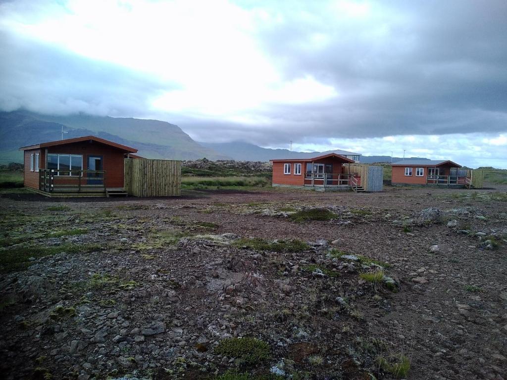 two houses in a field with mountains in the background at Langafjaran Cottages in Hjarðarfell