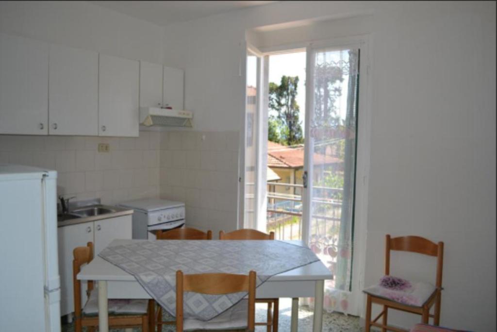 eine Küche mit einem Tisch und Stühlen sowie eine Küche mit einem Fenster in der Unterkunft Appartamento 5 in Ameglia