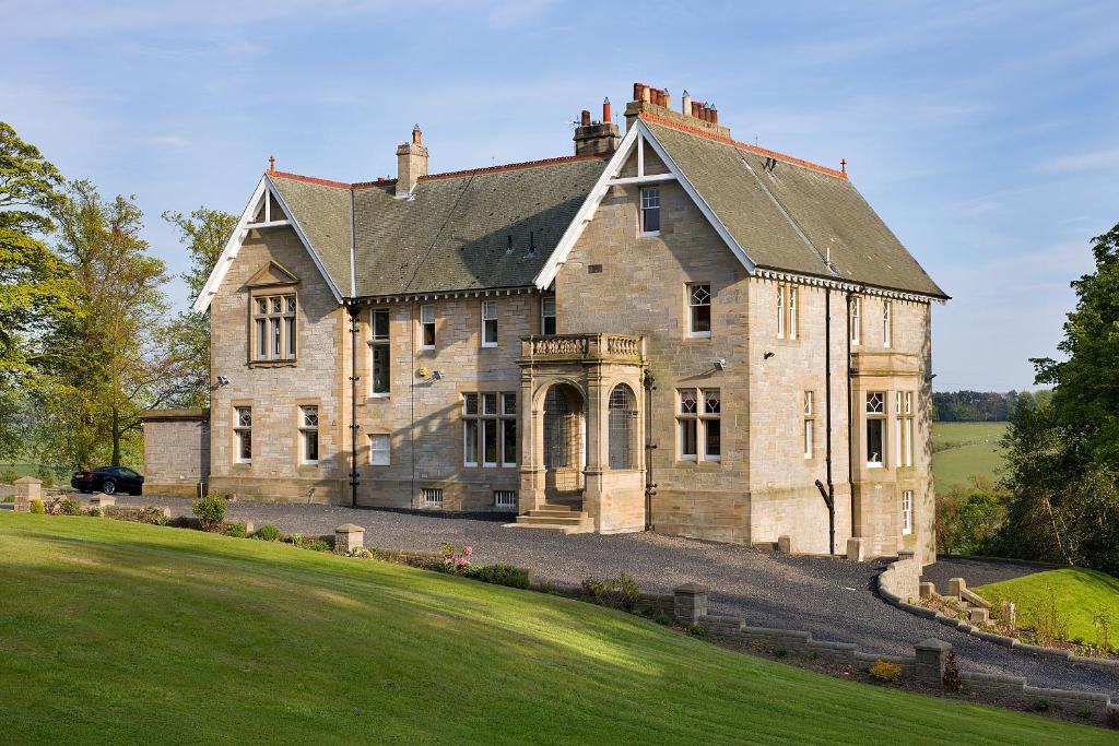 uma velha casa de pedra numa colina relvada em Balmule House em Dunfermline