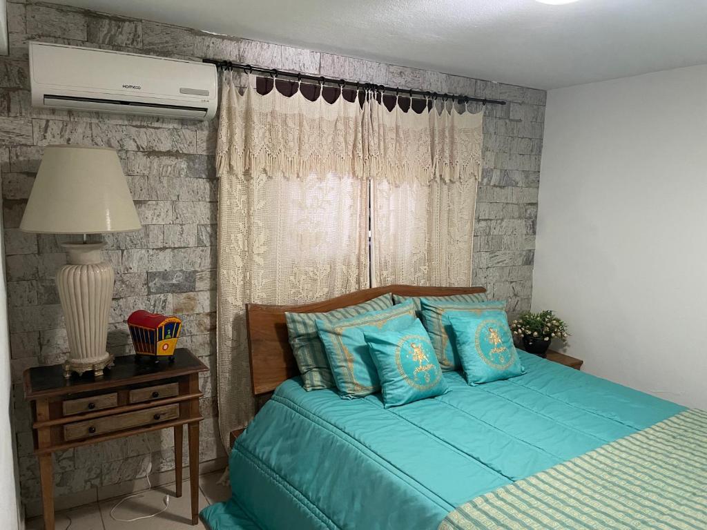 Un dormitorio con una cama con sábanas azules y una ventana. en Casa aconchegante com piscina em Tiradentes, en Tiradentes