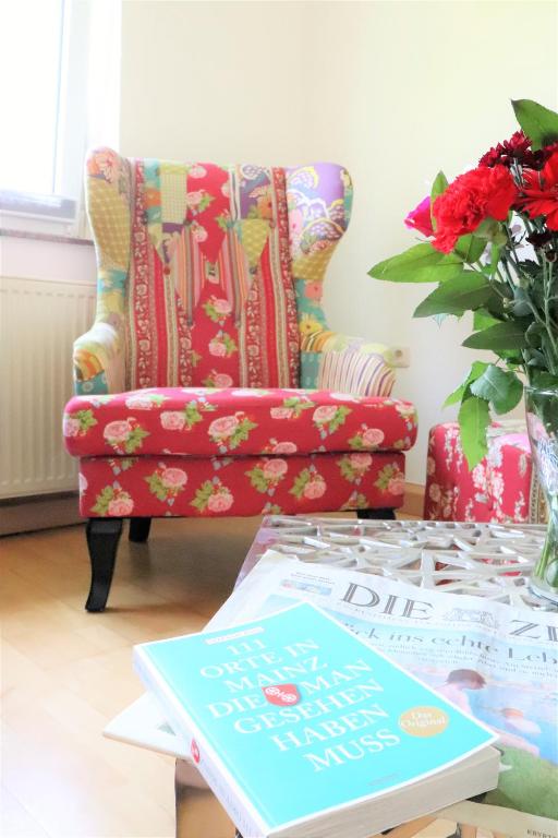 a living room with a chair and a table with a book at Gutenberg - helle und geräumige Wohnung in Uninähe in Mainz