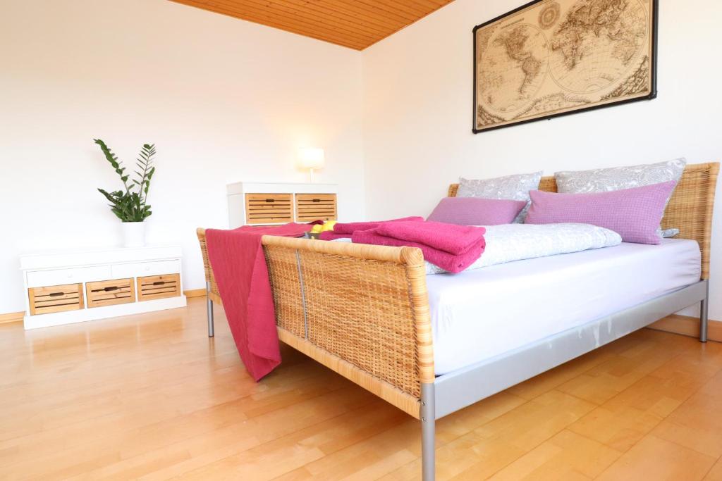 a wicker couch in a living room with pink and purple pillows at Gutenberg - helle und geräumige Wohnung in Uninähe in Mainz