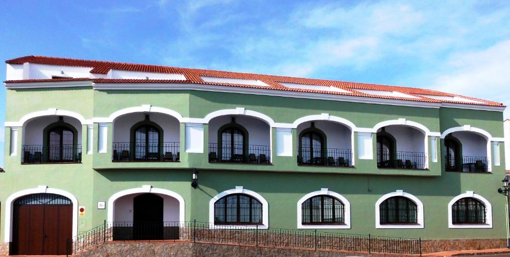 un edificio verde y blanco con techo rojo en Apartamentos Trinidad, en Alange