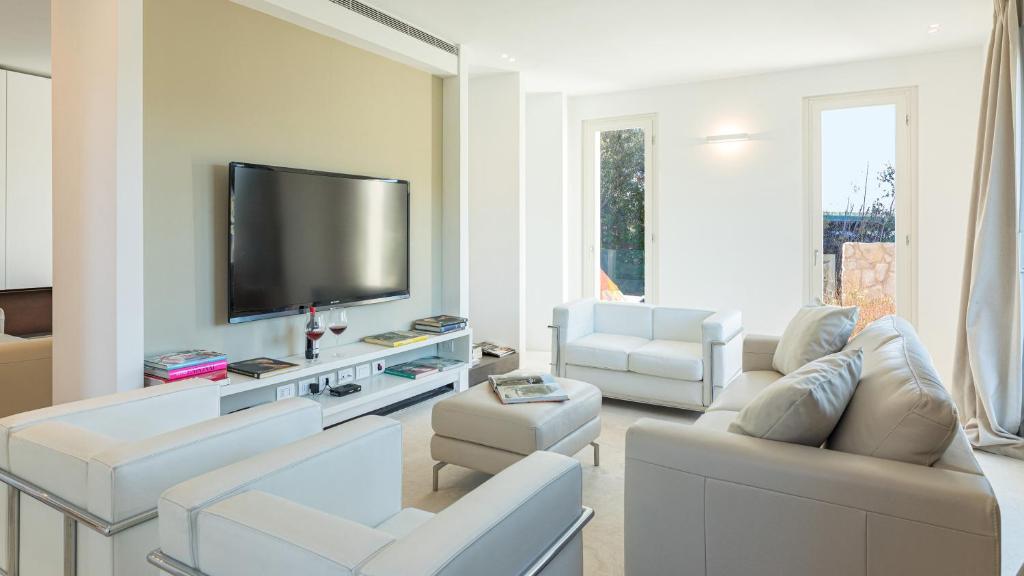 salon z białymi meblami i telewizorem z płaskim ekranem w obiekcie VILLA LE MANDRIE 7&2, Emma Villas w mieście Castiglione della Pescaia
