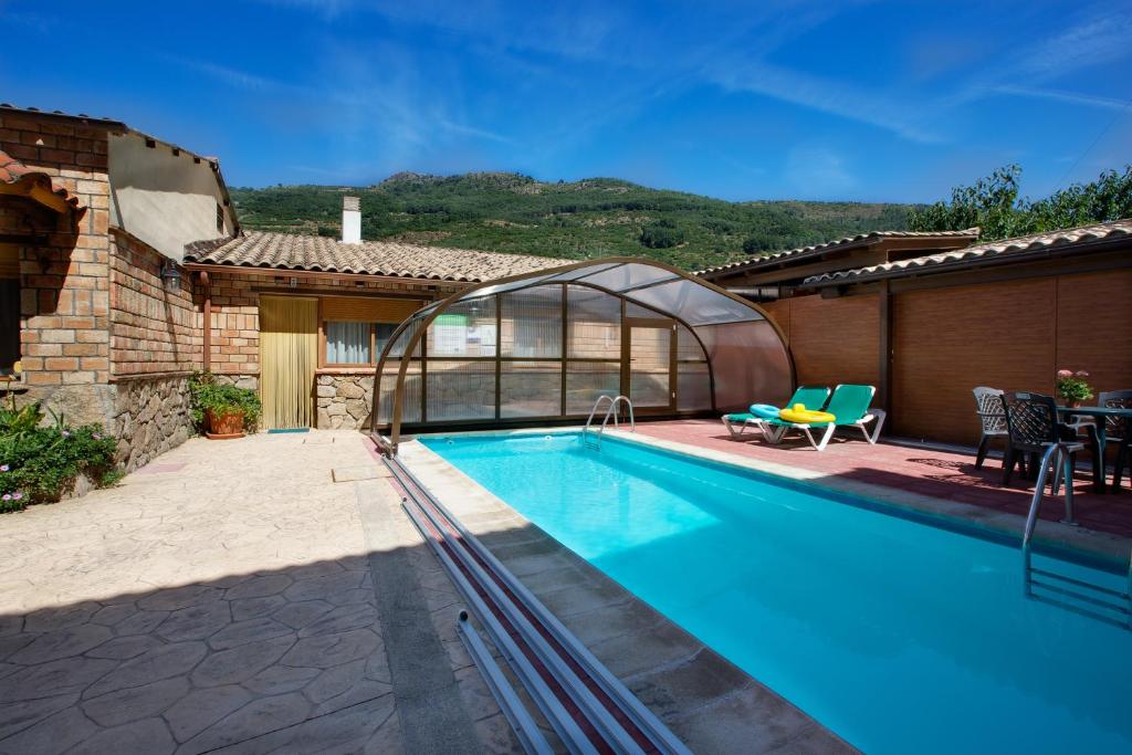 a swimming pool in front of a house at Casas Rurales Carroyosa del Jerte in Navaconcejo