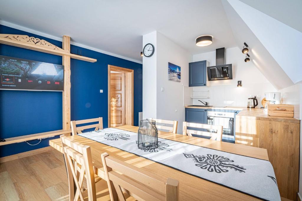 a kitchen and dining room with a wooden table and chairs at Aparteo Apartament Pod Wierchem in Kościelisko