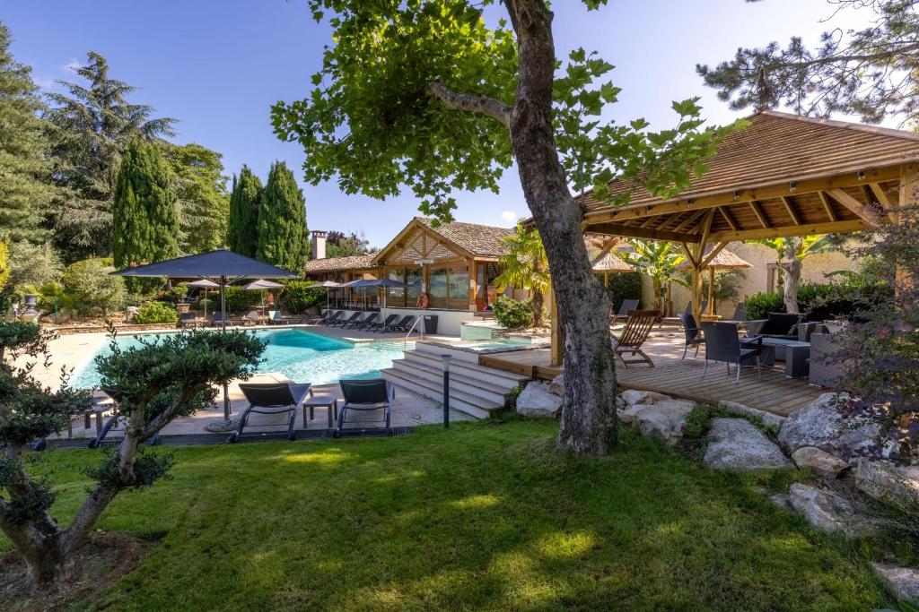 a backyard with a pool and a deck with chairs and a house at Hotel Village Motel in Tournus