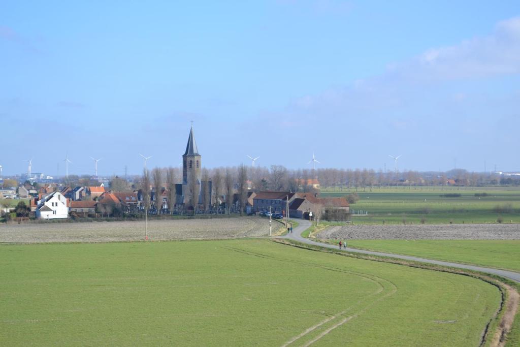 un campo verde con una chiesa sullo sfondo di De Maretak a Meetkerke