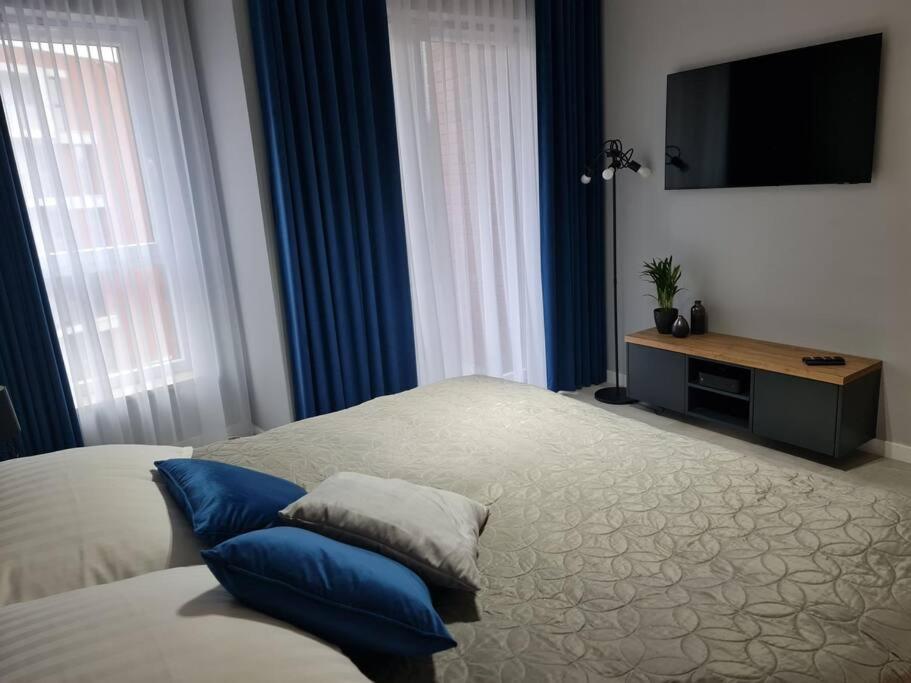 a bedroom with a bed with blue curtains and a flat screen tv at Bastion Apartament in Gdańsk
