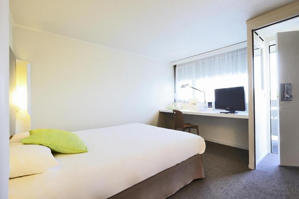 a bedroom with a bed and a desk with a computer at Campanile Auxerre - Monéteau in Monéteau