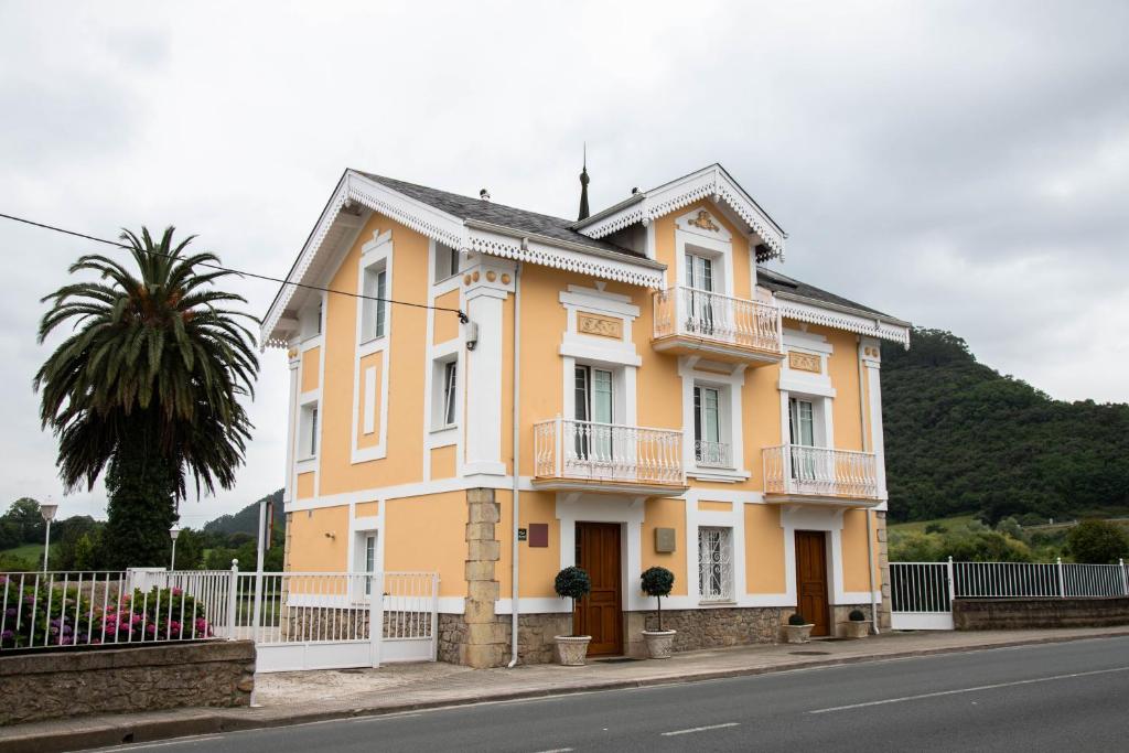 una casa amarilla al lado de una calle en Apartamentos Villa Fresnedo, en Solares