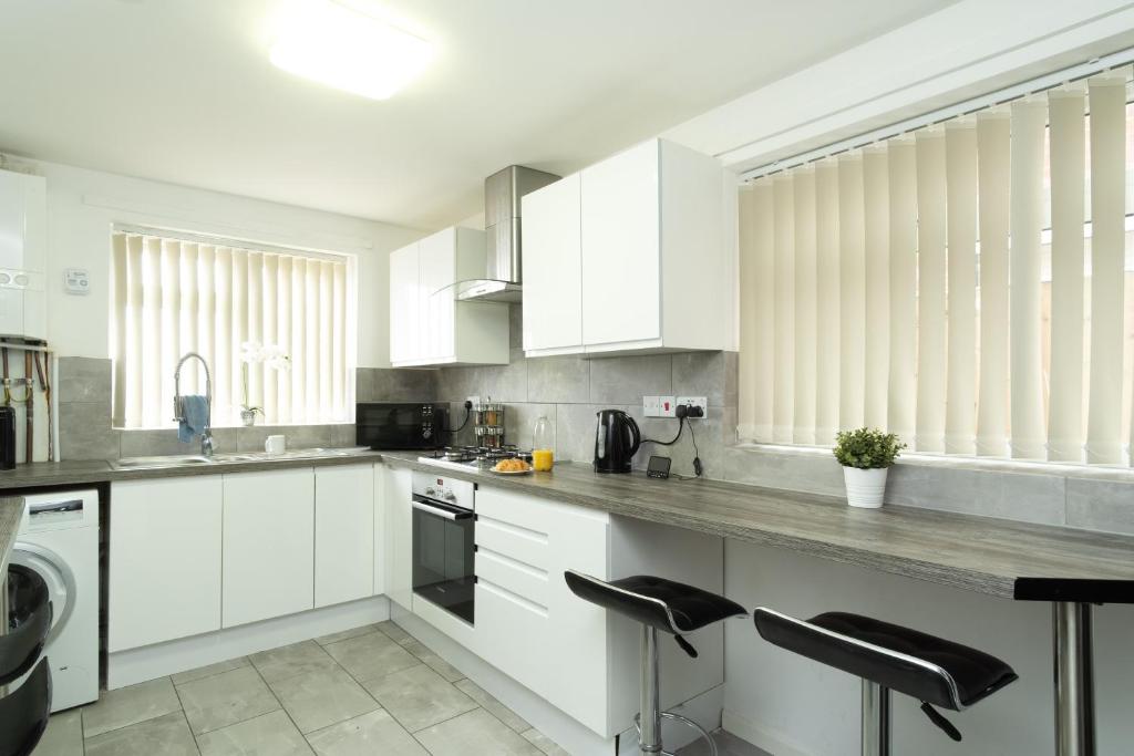 una cocina blanca con armarios blancos y electrodomésticos negros en Dorchester House en Coventry