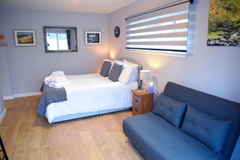 1 dormitorio con 1 cama y 1 sofá azul en 13 Matheson Place, en Portree