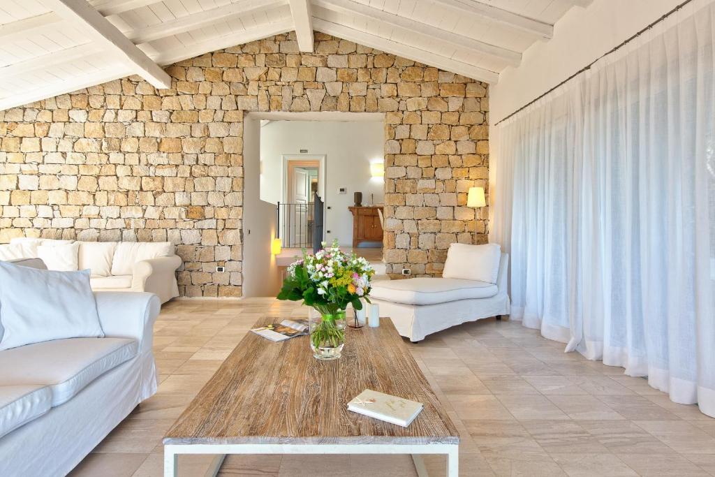 sala de estar con muebles blancos y pared de ladrillo en Villa Gelsomino a soli 500 mt dal mare con piscina privata e vista mare, en Castiadas