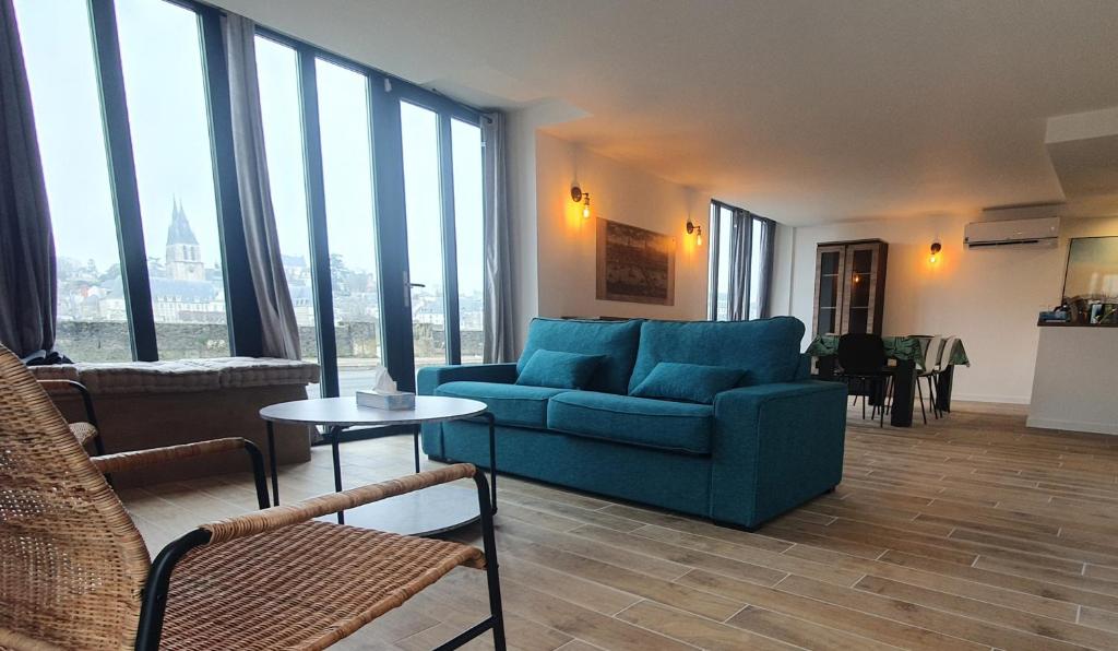 - un salon avec un canapé bleu et de grandes fenêtres dans l'établissement "Gîte Le Relais Viennois" vue sur Loire & linge inclus, à Blois