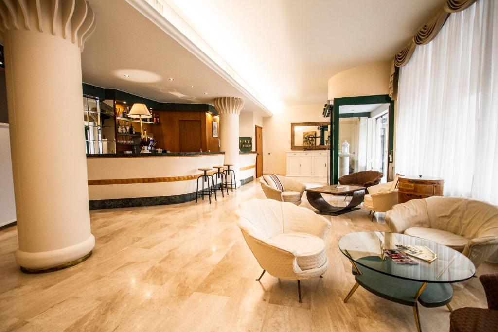 a living room with white furniture and a column at Hotel Elefante in Montichiari