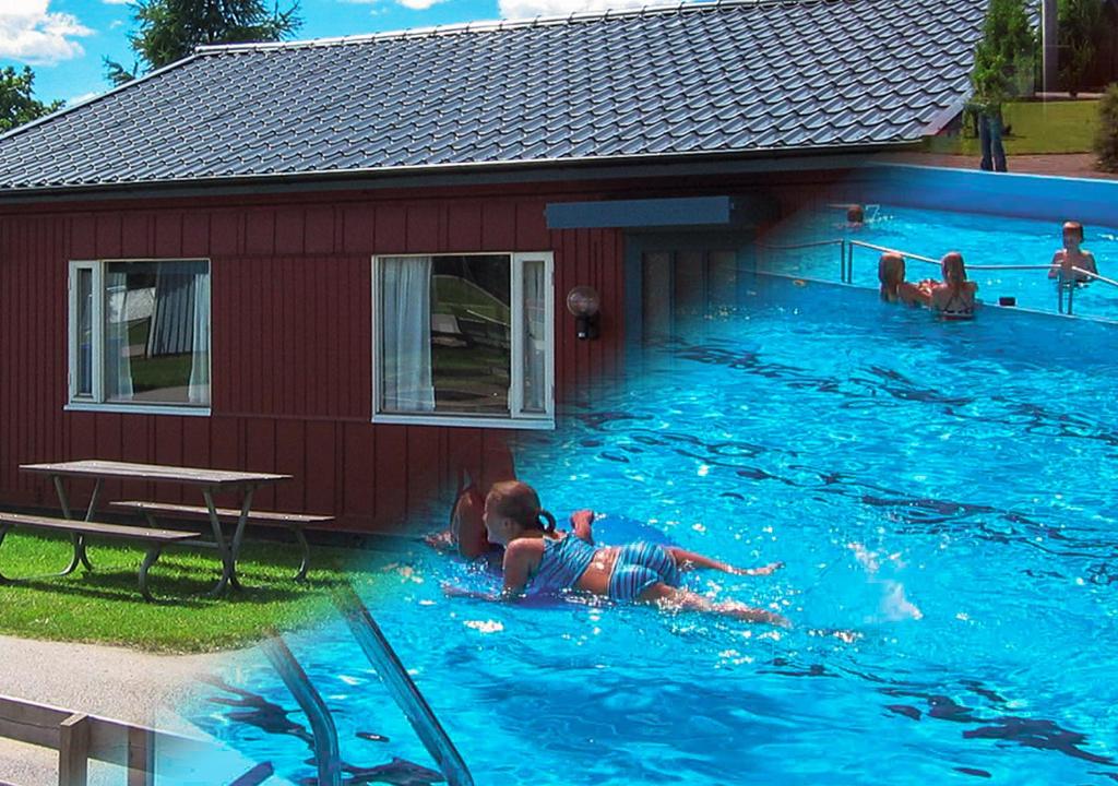 a child in a swimming pool next to a house at Ätrans Stugby & Fritidsanläggning in Ätran