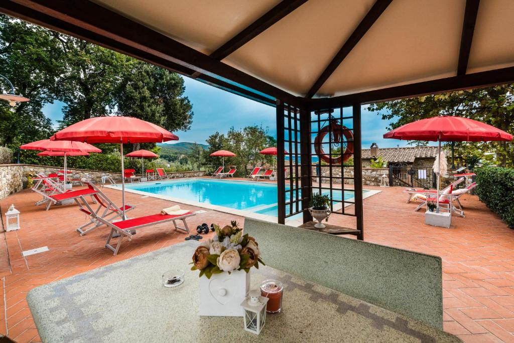 a pool with red umbrellas and a table with flowers at Agriturismo La Ghiraia in Santa Luce