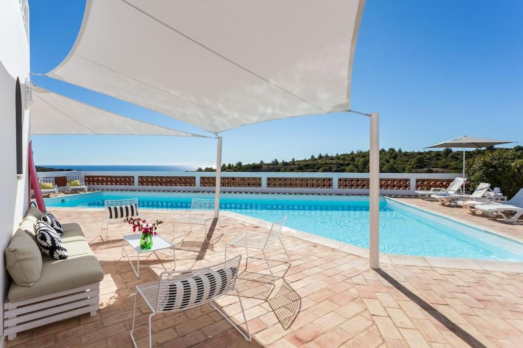 una piscina con sedie e ombrellone bianco di Ocean view beach villa a Budens