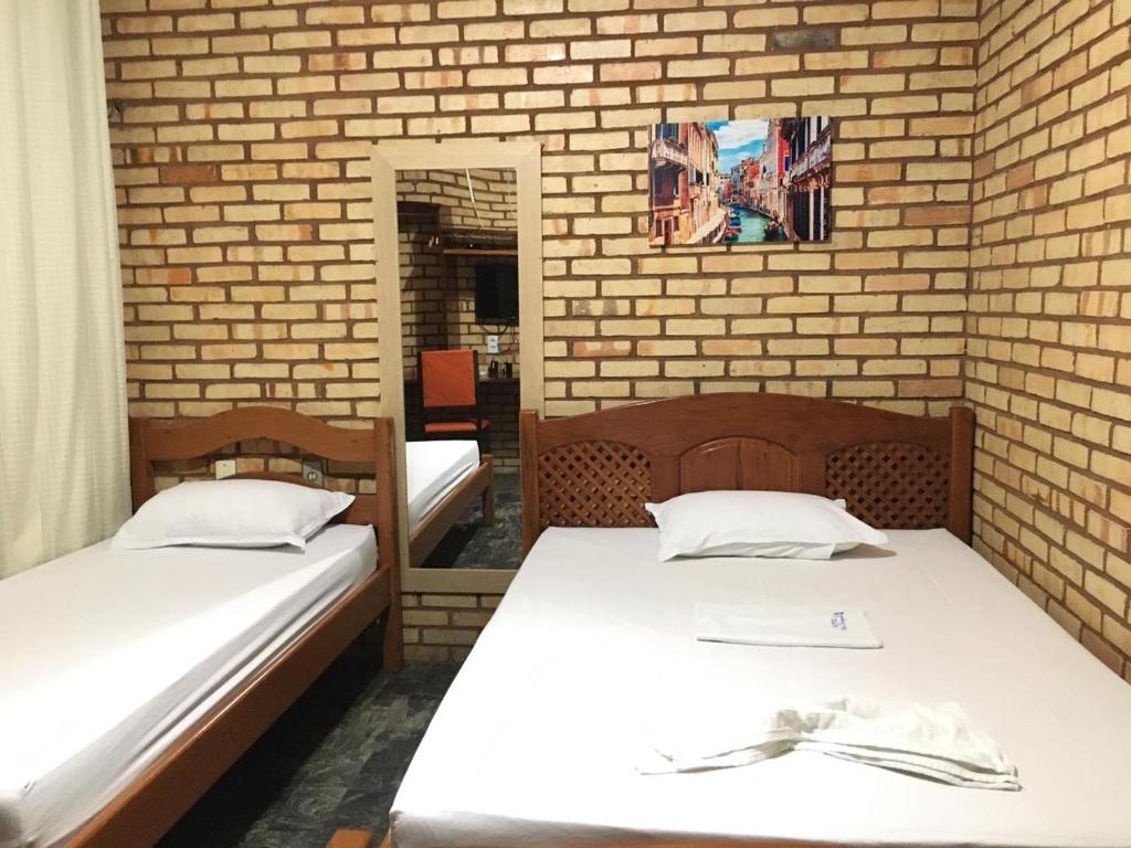 two beds in a room with a brick wall at Hotel Olho D'água - Baturité in Baturité
