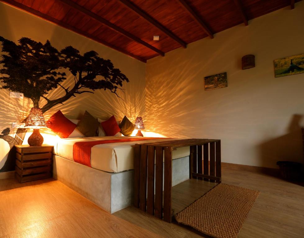 a bedroom with a bed with a tree on the wall at Kele Yala in Yala