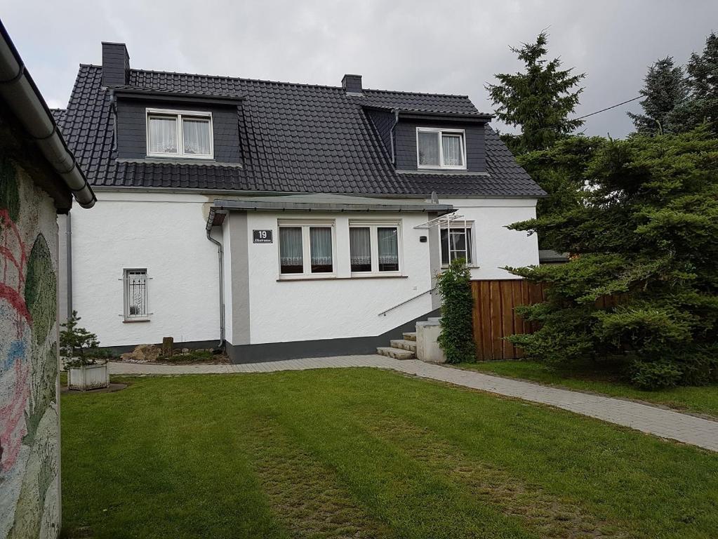 a white house with a fence and a yard at Ferienwohnung Fam. Schade in Beilrode