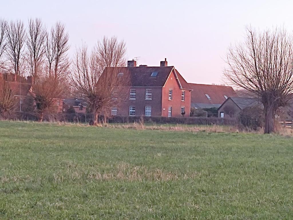 a large red brick house in front of a field at The Cheesehouse in Salisbury