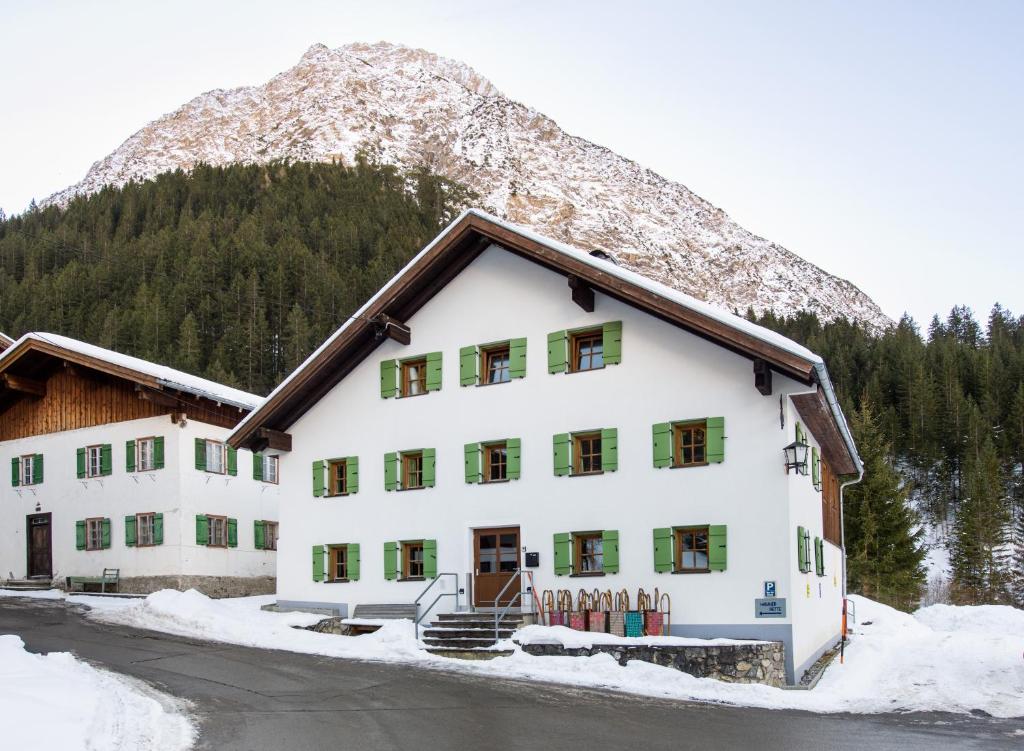 un grand bâtiment blanc avec une montagne en arrière-plan dans l'établissement Stern LODGE im Bergparadies Lechtal, à Boden