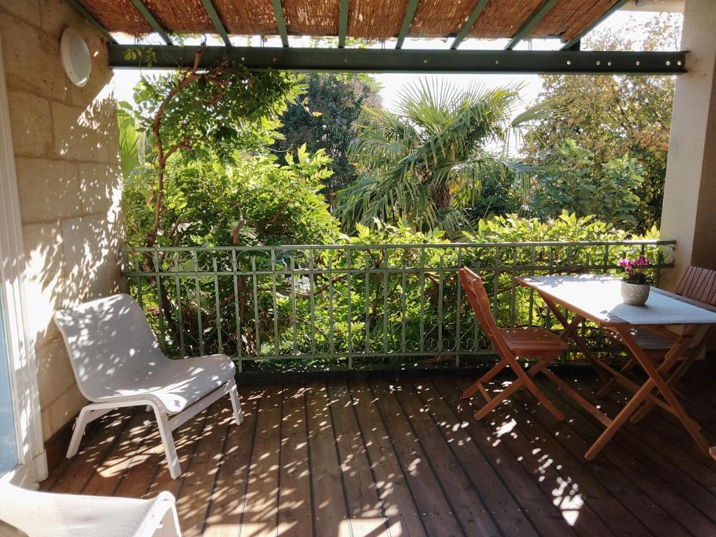 un patio con 2 sillas, una mesa y una valla en La maison botanique, en Castillon-la-Bataille