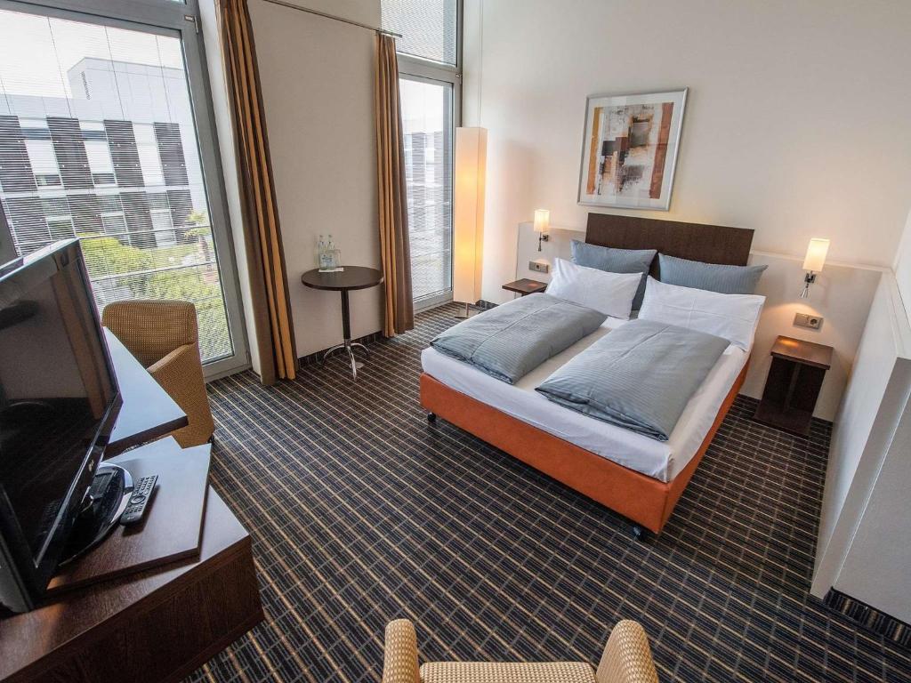 Habitación de hotel con cama y TV de pantalla plana. en Livenwork Hotel & CoWorking GVZ Ingolstadt en Ingolstadt